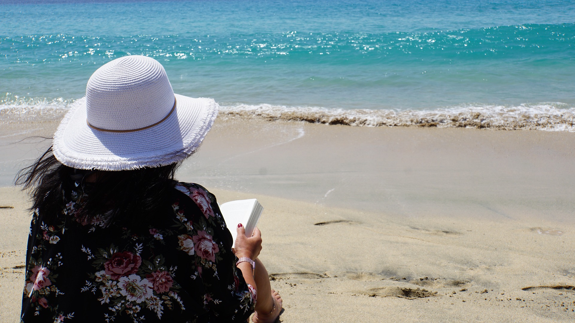 Lady reading a book on the beach in the Caribbean